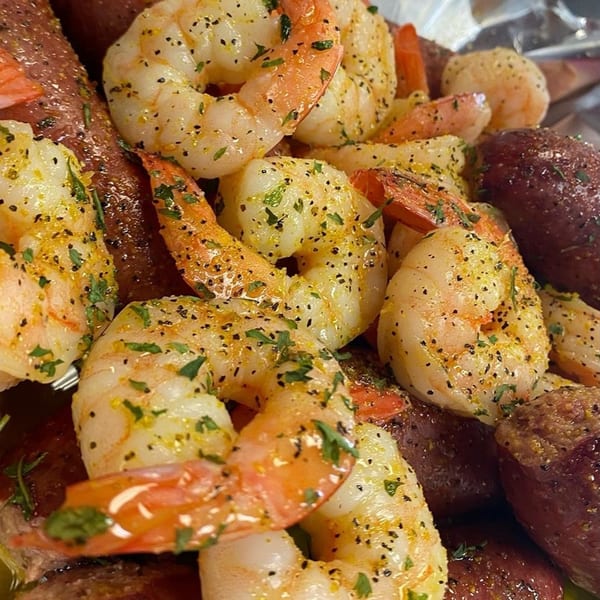 Close-up of Krab Kingz seasoned shrimp and red potatoes, garnished with herbs and spices.