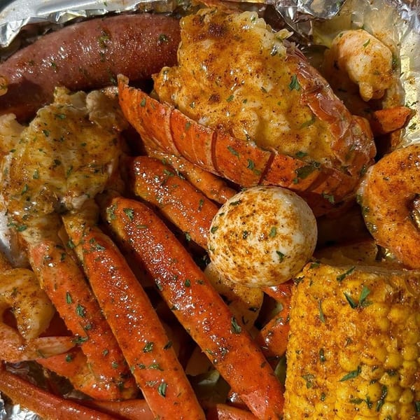 Krab Kingz seafood boil with lobster, crab legs, sausage, corn, and potatoes in foil.